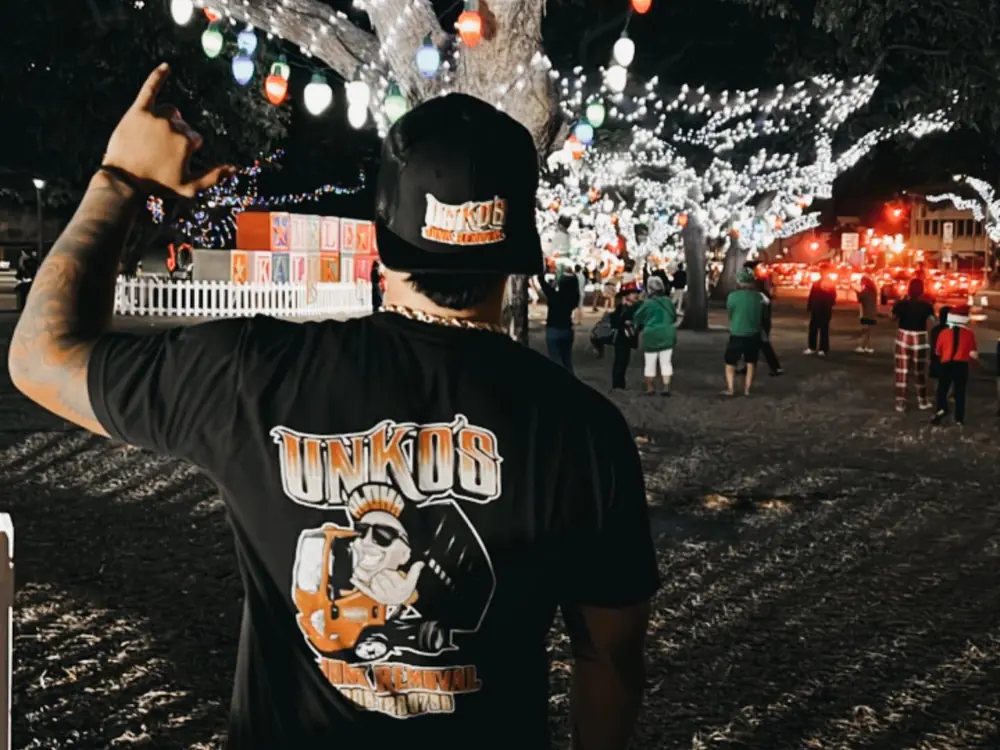 The back of an Unko's shirt with the mascot print, under strings of holiday lights.