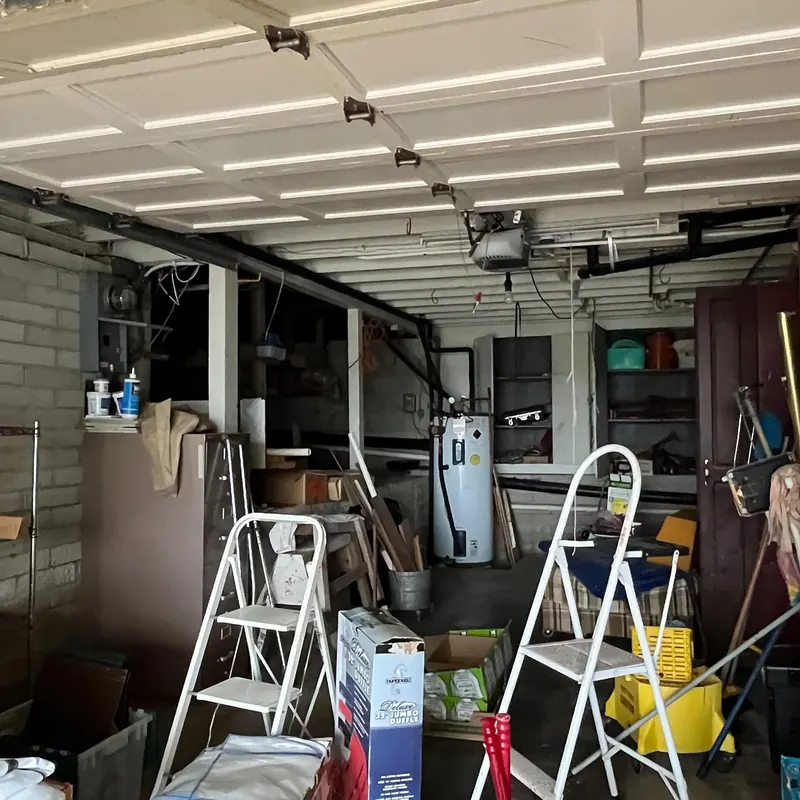 A garage full of boxes, step ladders, tools and household gear waiting to be cleared.